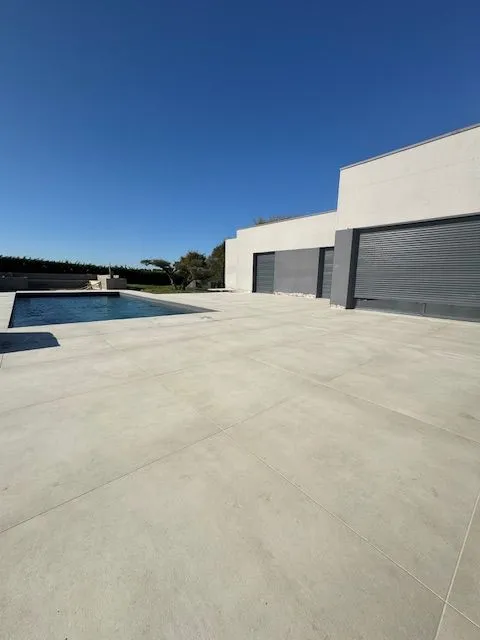 Carrelage clair autour d’une piscine devant une façade contemporaine