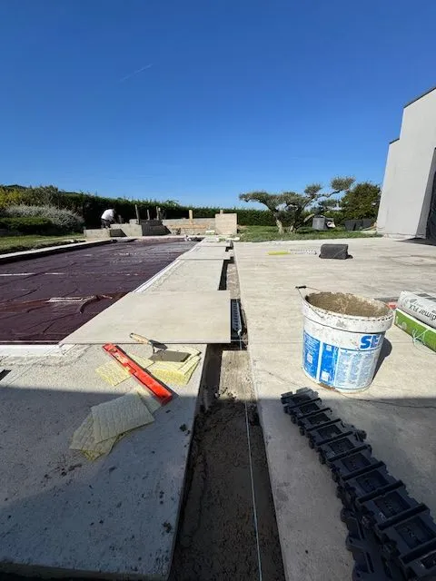 Pose des carreaux clairs le long du bassin avec matériel de chantier